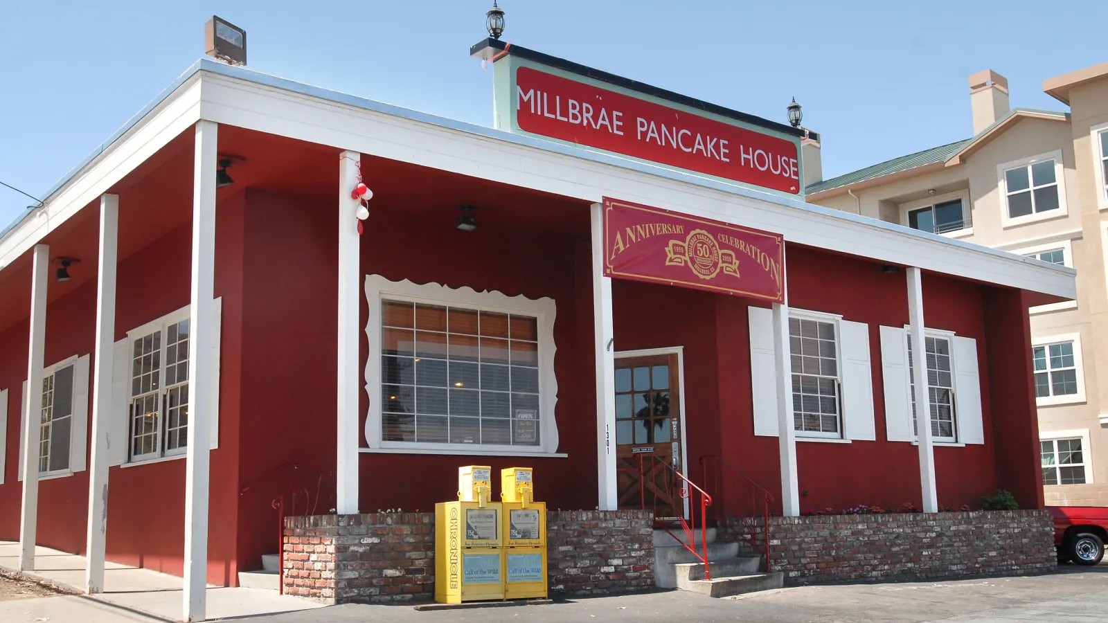Exterior view of the historic Millbrae Pancake House with its red facade and classic signage.