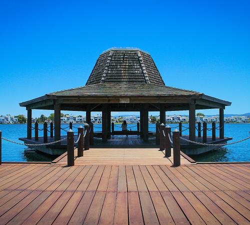 Gazebo afloat on Foster City lagoon surrounded by clear blue sky and calm water.